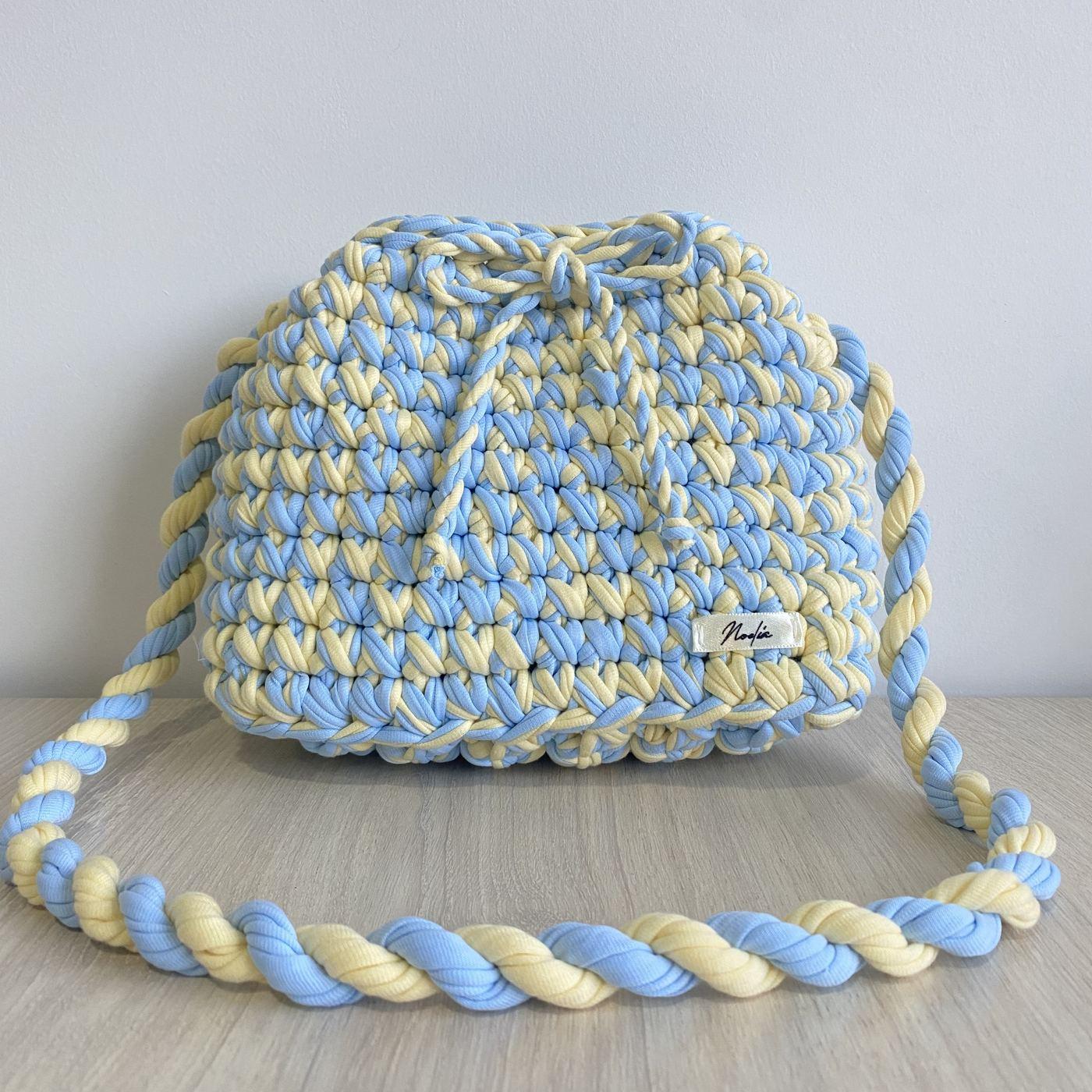Cartera tejida a crochet en trapillo celeste y crema, con cordón trenzado